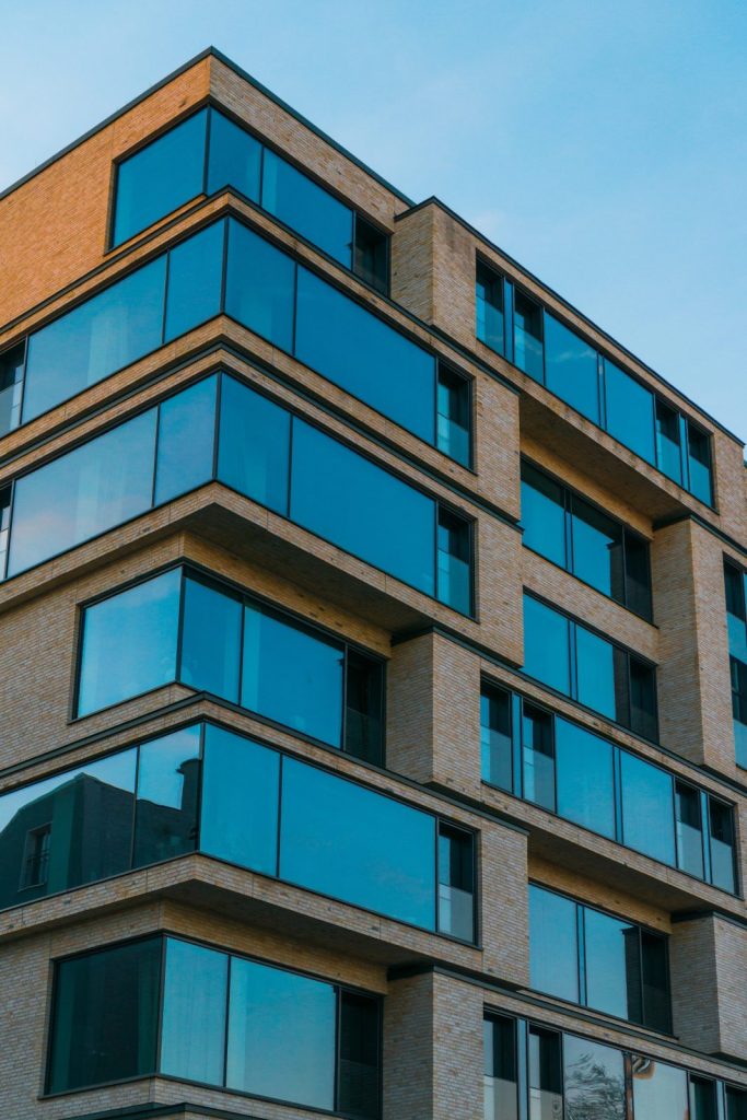 The glazed corner of an apartment building against a clear sky