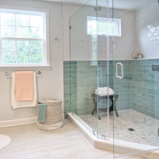 A frameless glass shower door in a pale tiled bathroom