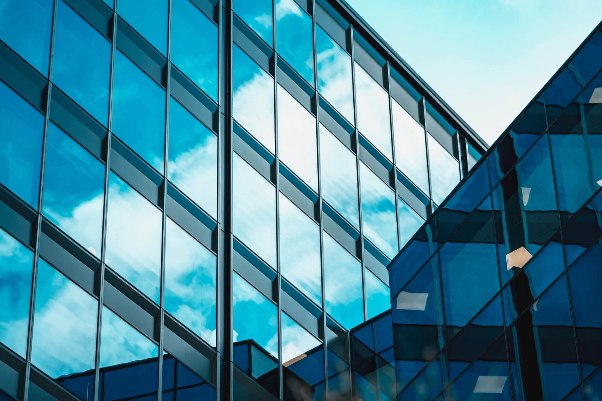 An angled blue-glass curtain wall facade against the sky