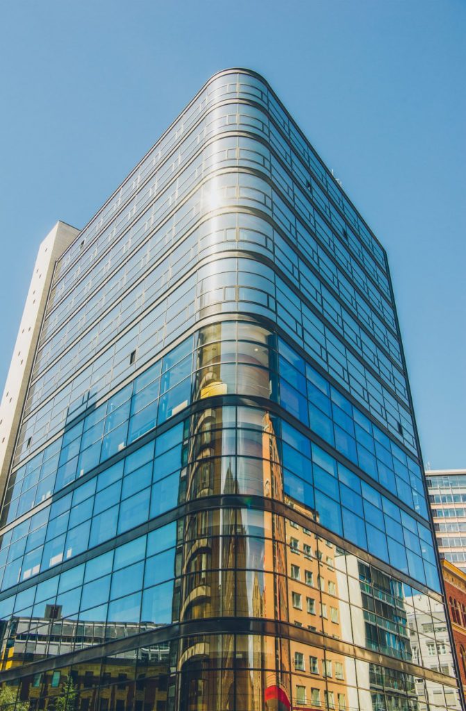 A curved glass office tower reflecting the buildings opposite