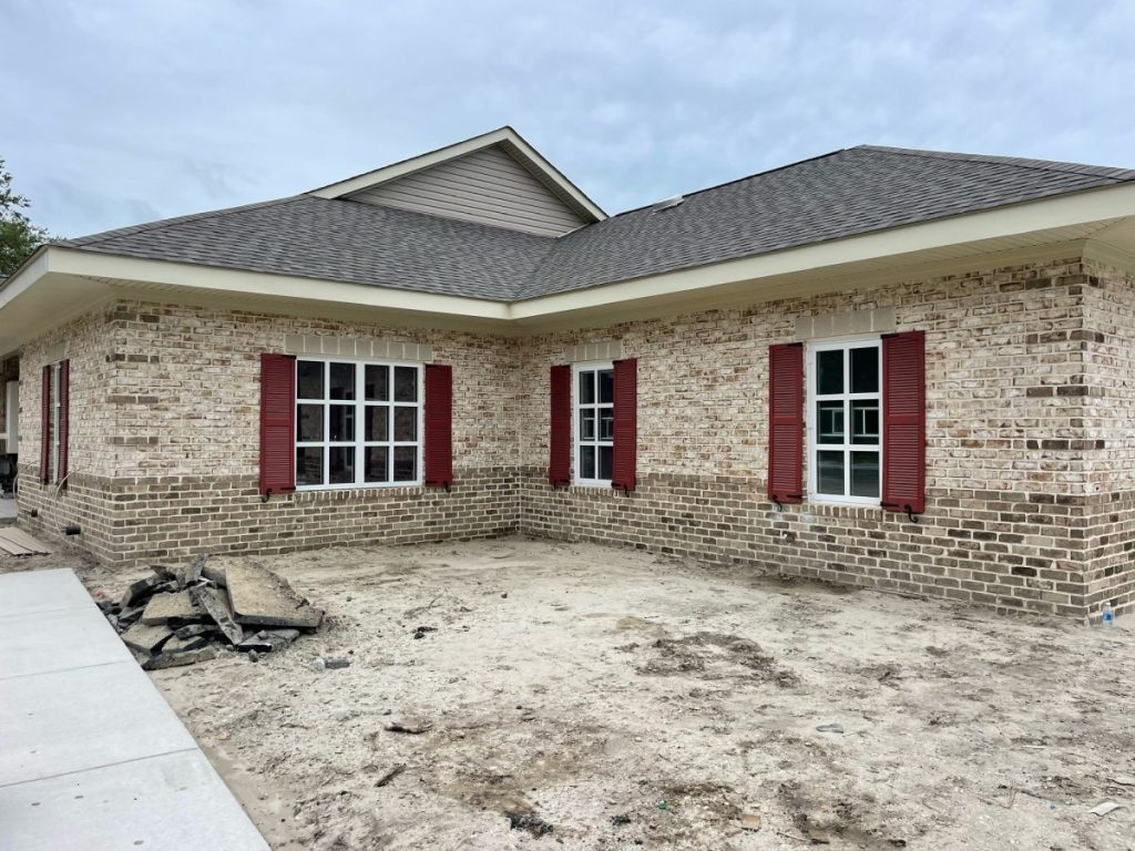 New brick home with white windows and red shutters