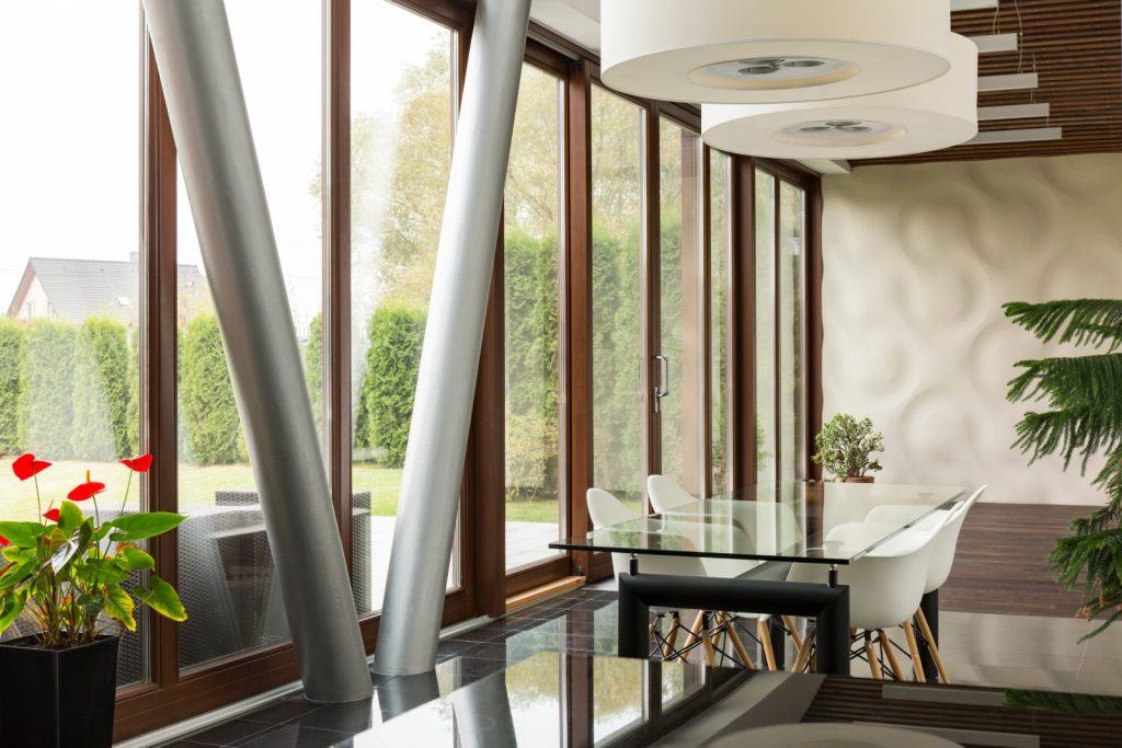 A dining space behind full-height glazing looking onto a garden
