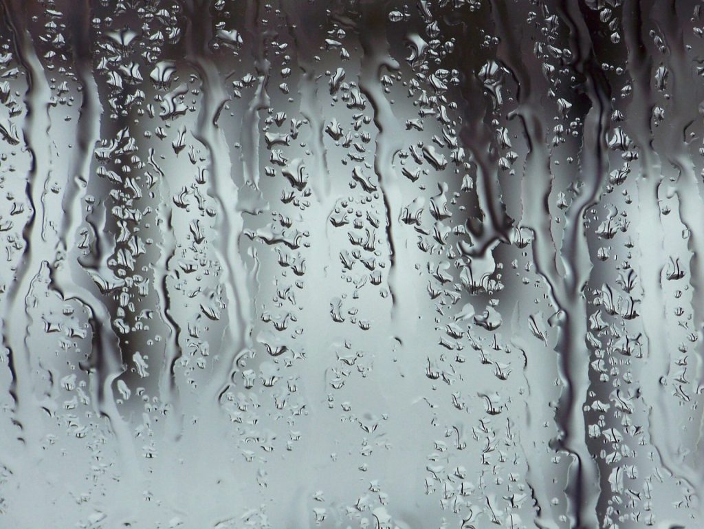 Water running down a textured glass surface, breaking the light behind it